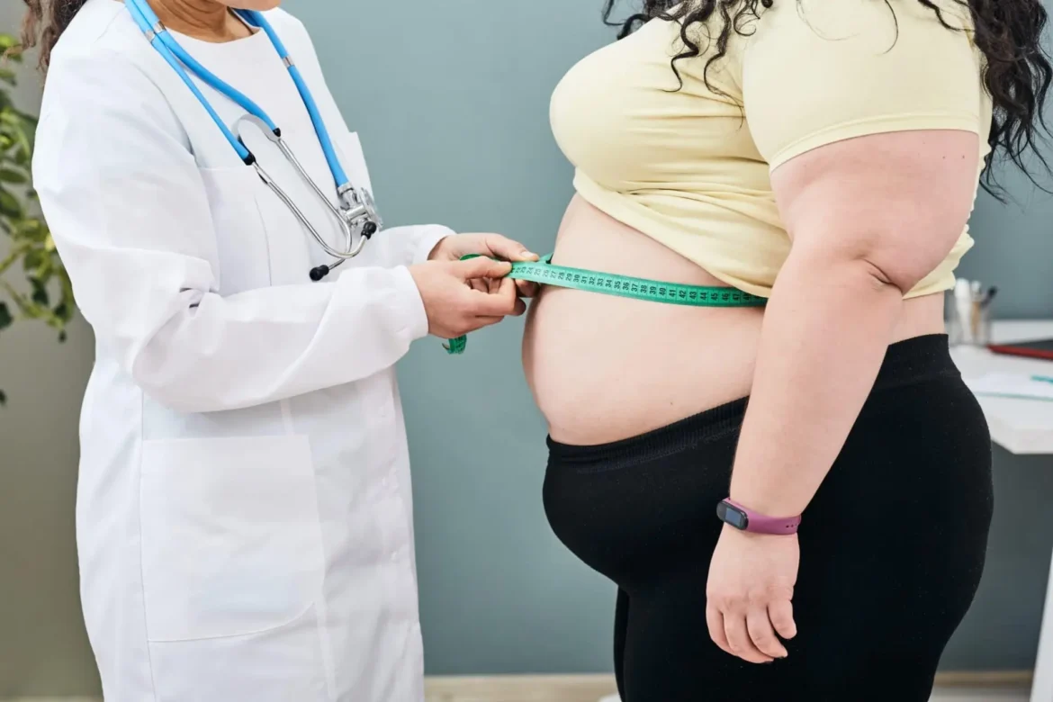 Medicul măsoară circumferința abdominală a unei paciente supraponderale pentru evaluarea riscurilor în sarcină cauzate de obezitate