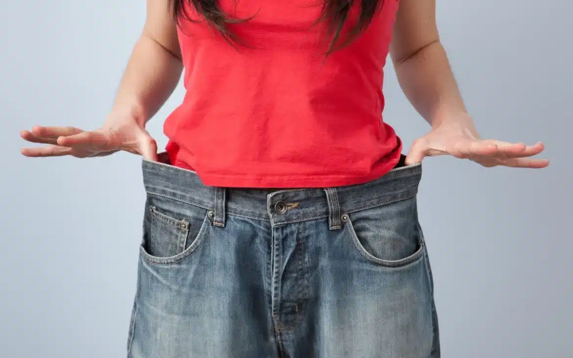 Pacient care a slăbit semnificativ după operația de chirurgie bariatrică, ținând pantalonii largi în fața abdomenului