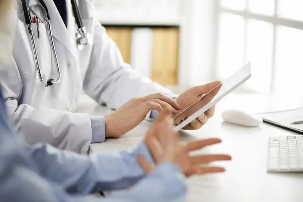 Medicul discută cu pacientul și analizează investigațiile preoperatorii pe tabletă înainte de chirurgia bariatrică.