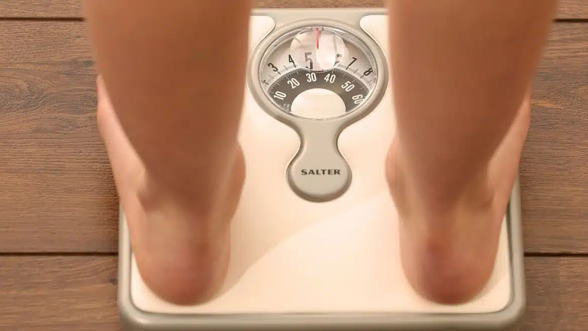 Persoană cântărindu-se pe un cântar, simbolizând controlul greutății după operația gastric sleeve