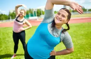 Pacientă supraponderală făcând exerciții fizice ușoare în aer liber după intervenția bariatrică