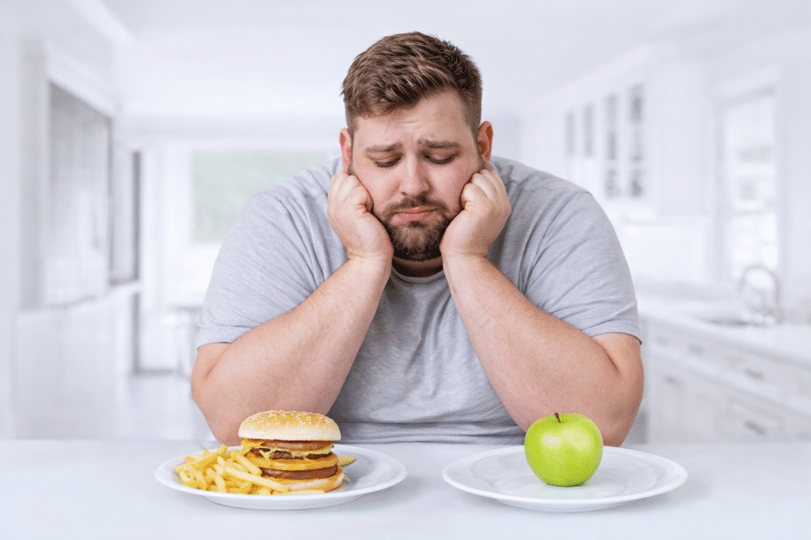 Bărbat supraponderal afectat de mâncatul emoțional, confruntat cu alegerea dintre alimente nesănătoase și opțiuni sănătoase
